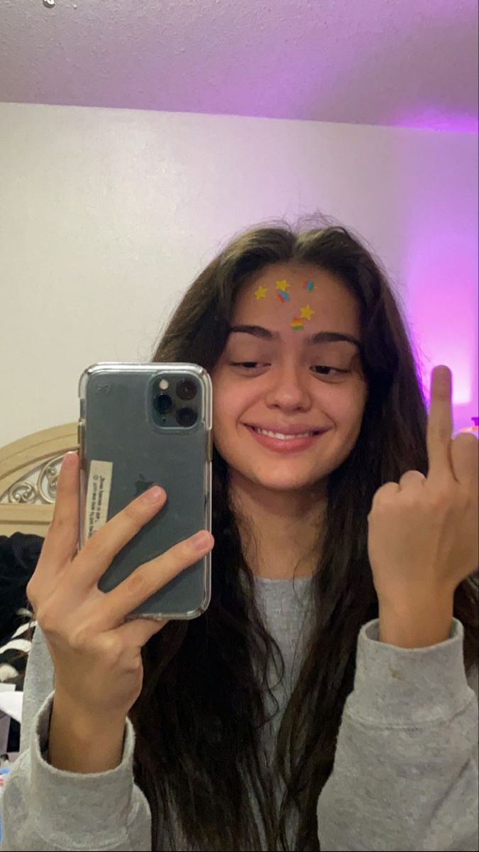 a girl is holding up her cell phone to show the peace sign with both hands