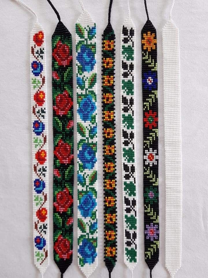 four beaded bracelets with flowers are hanging on a white tablecloth and one has black string