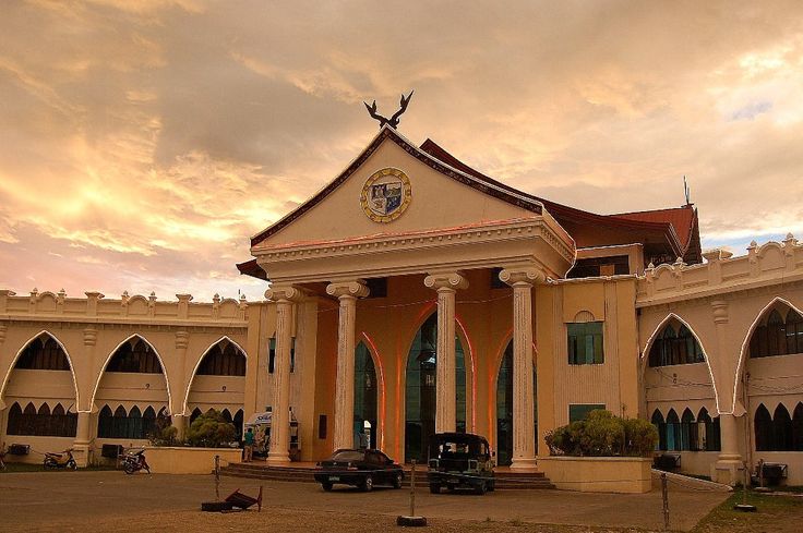 an old building with columns and arches on the front, under a cloudy sky at sunset