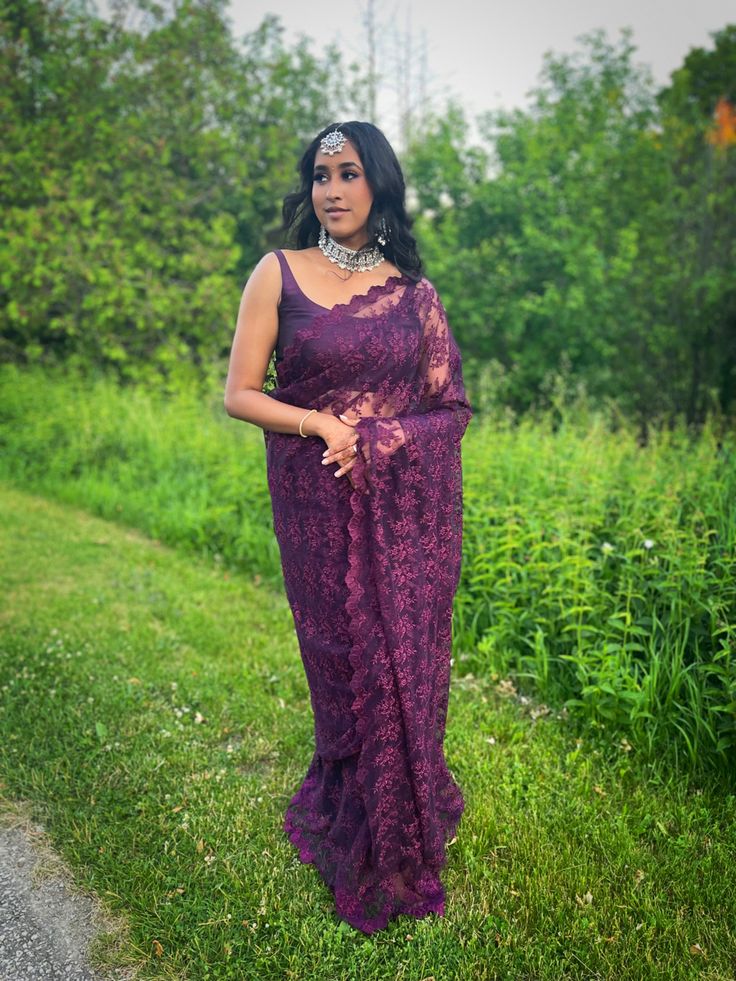 a woman wearing a purple dress standing in the grass