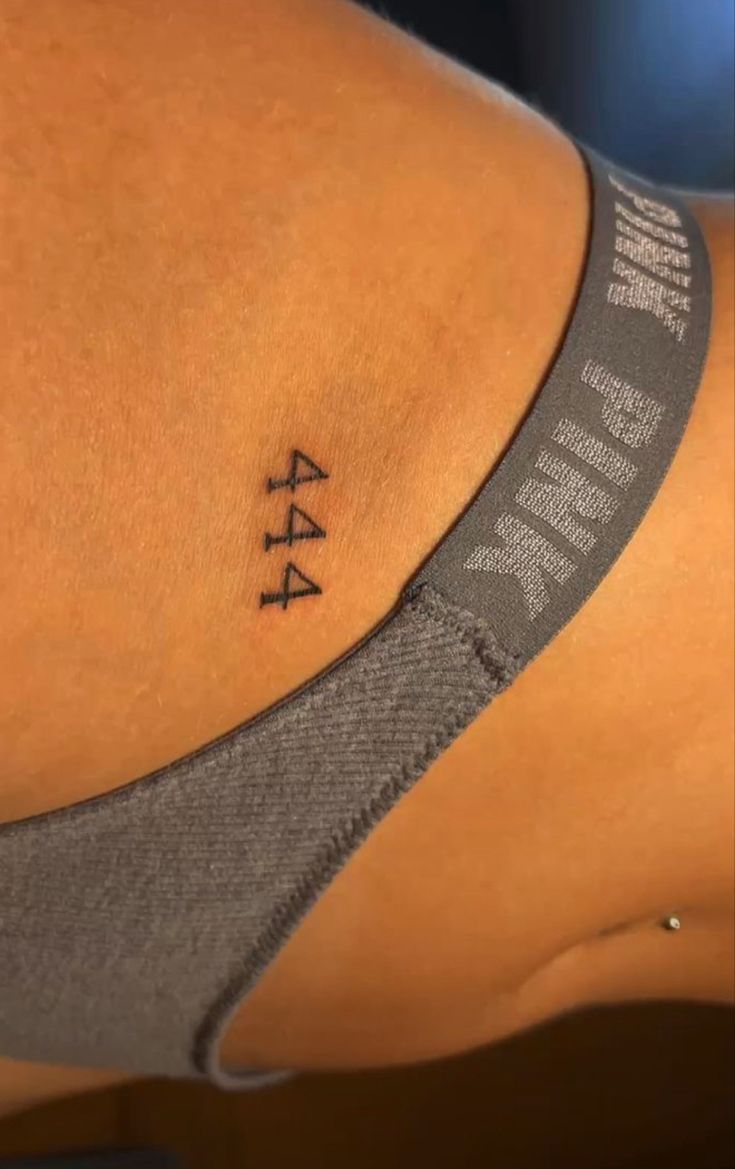 a woman's lower back tattoo with an arrow on her left side ribcage