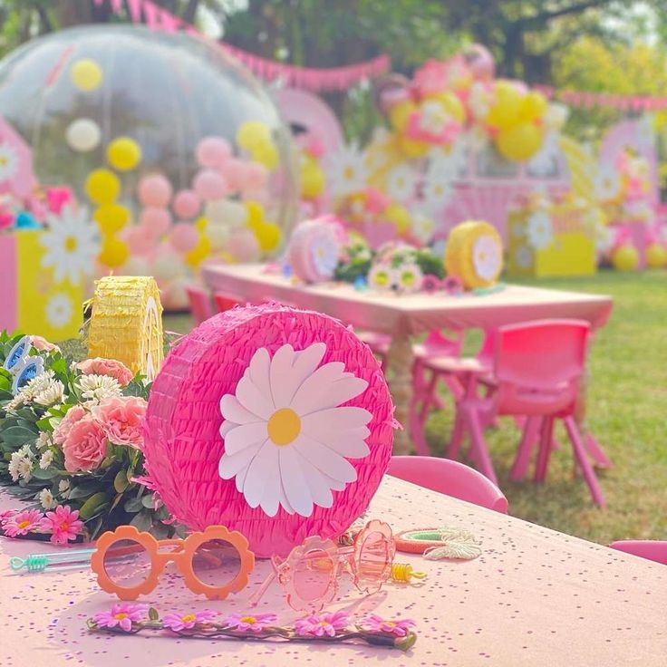 a pink table topped with lots of flowers and sunglasses