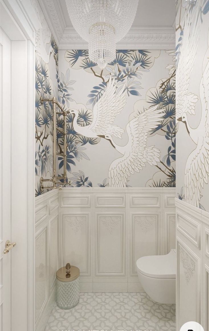 a white bathroom with wallpaper and chandelier hanging from the ceiling next to a toilet