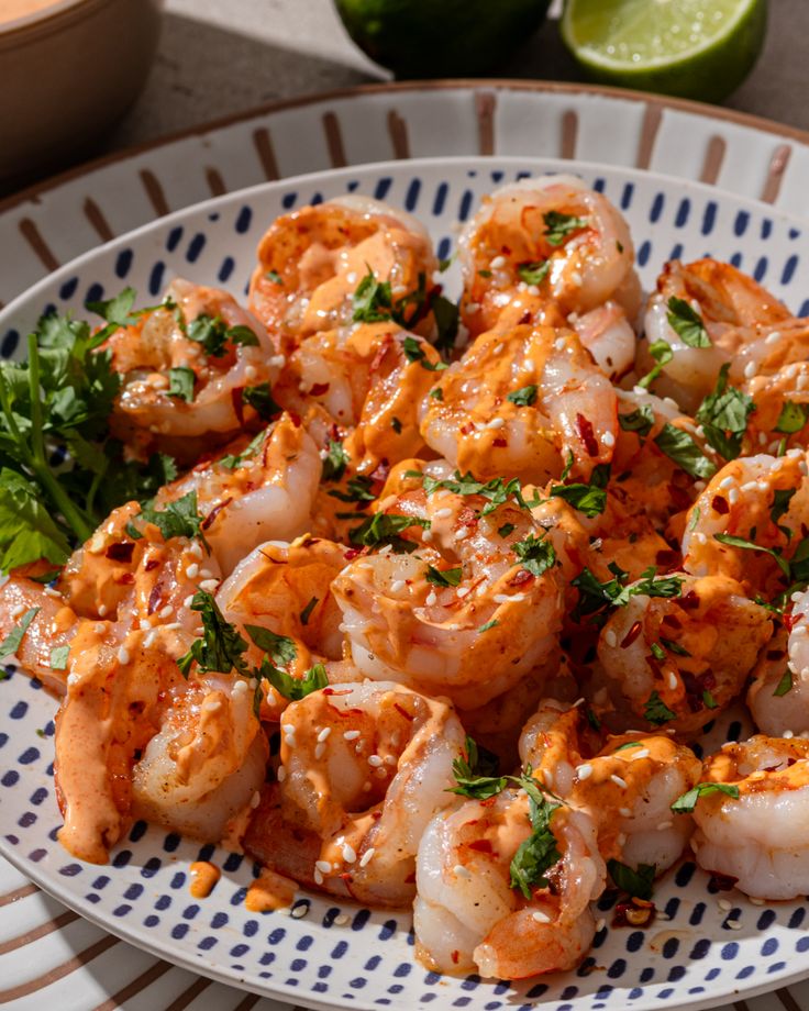 a white plate topped with shrimp covered in sauce and garnished with cilantro