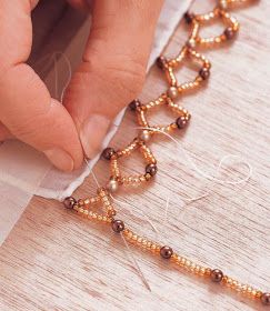 a woman is making beaded bracelets on a piece of paper with scissors and thread