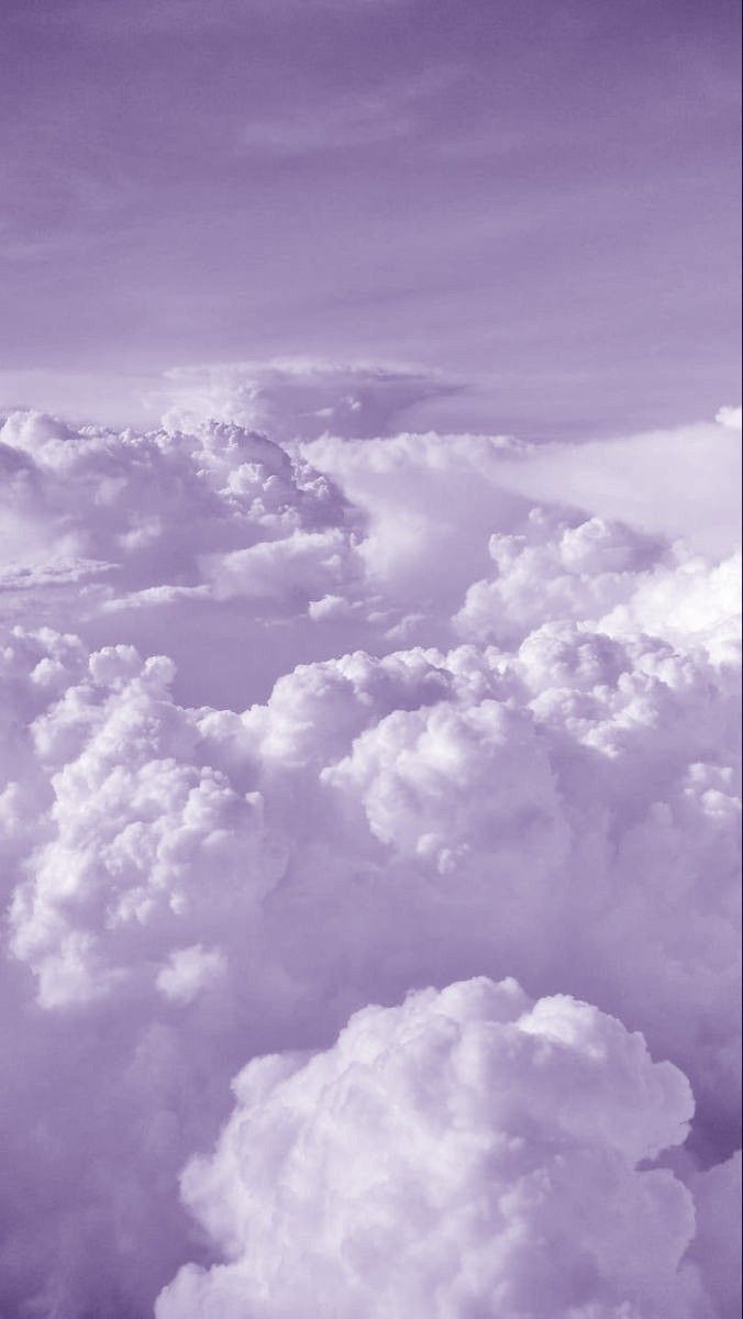 an airplane is flying high above the clouds in this black and white photo with purple hues