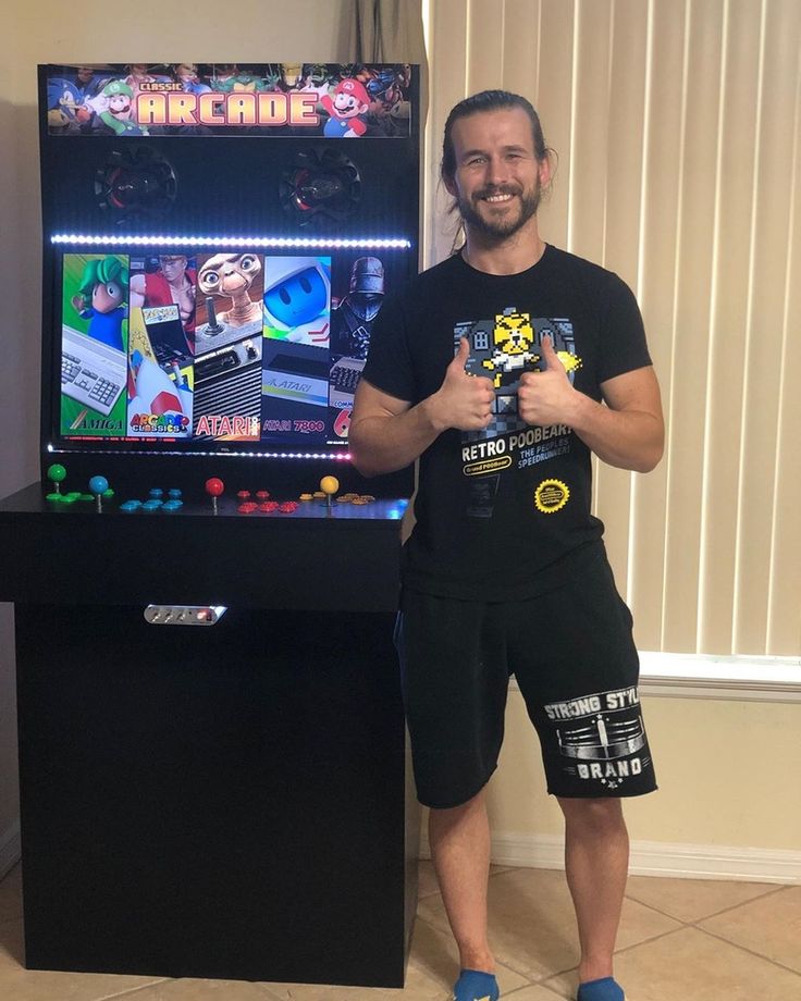 a man standing in front of a video game machine holding a remote control and smiling at the camera