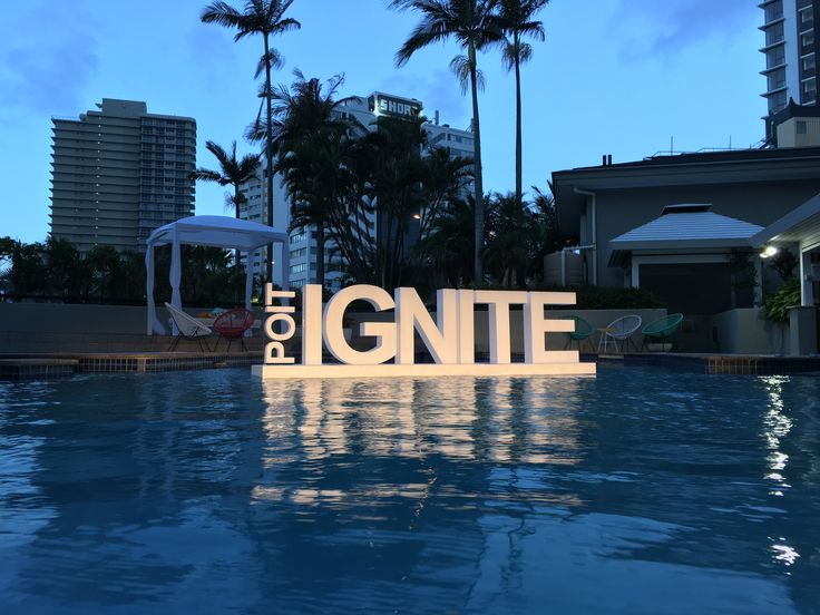 the word ignte is placed in front of a swimming pool with palm trees and buildings in the background