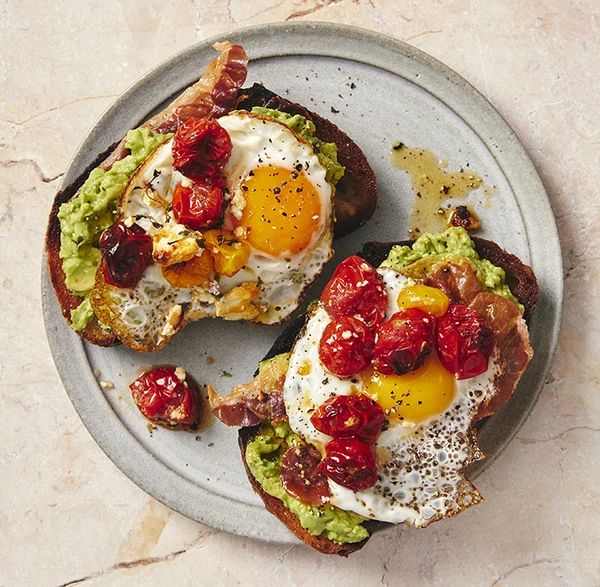 two pieces of toast with an egg and tomatoes on them, sitting on a plate