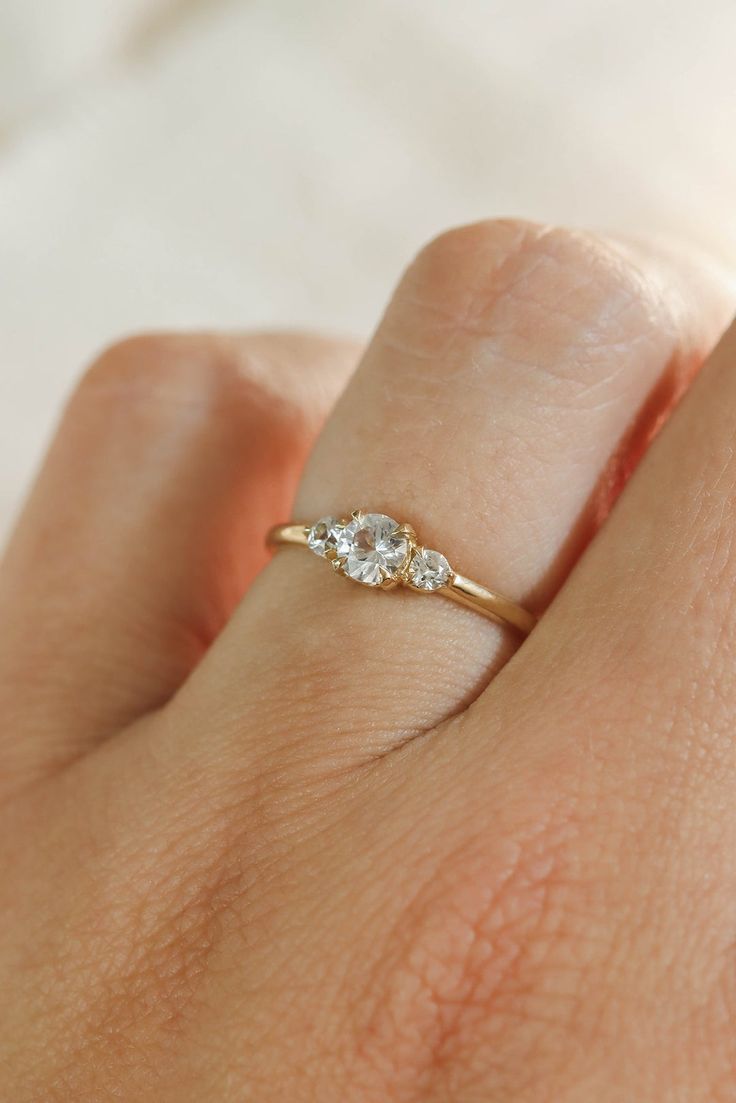 a woman's hand with a diamond ring on top of her finger, showing the side view