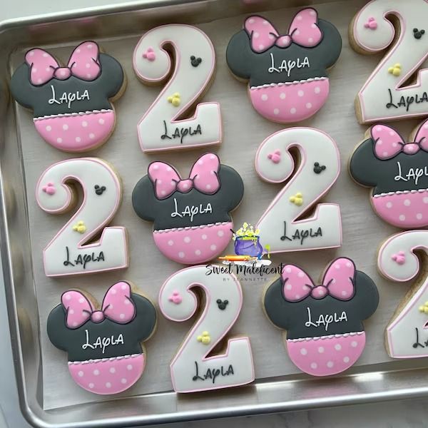 decorated cookies in the shape of numbers with minnie mouse ears and bows are displayed on a tray