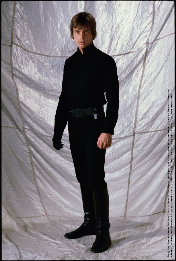 a man dressed in black standing next to a white backdrop