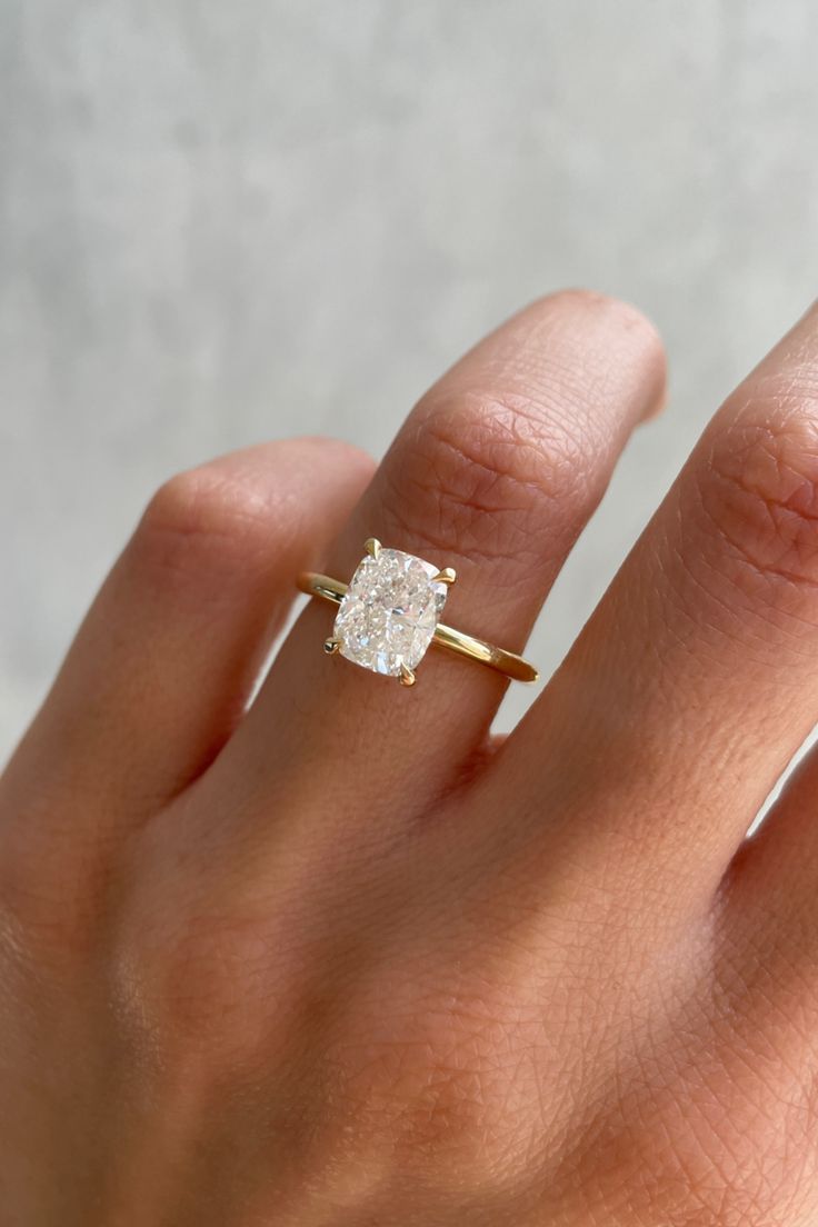 a woman's hand with a diamond ring on top of her finger, showing the center stone