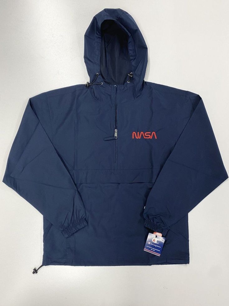 This NASA Champion half-zip packable jacket is a wind and rain resistant polyester jacket with a detailed NASA embroidery design. It has a practical hood, front kangaroo pocket, and zipped pouch pocket which you can pull out and use to scrunch the jacket into for convenient storage. This jacket ships separately directly from the supplier. Please allow 2-8 days from purchase date for order fulfillment. Color: Navy Product Details: • 100% polyester micro poplin • Wind and rain resistant • Half zip Navy Windbreaker With Pockets For Hiking, Hooded Camping Jacket With Pockets, Long Sleeve Windbreaker With Pockets For Camping, Camping Hooded Jacket With Pockets, Long Sleeve Camping Windbreaker With Pockets, Hooded Jacket With Pockets For Camping, Waterproof Nylon Half-zip Windbreaker, Waterproof Half-zip Nylon Windbreaker, Casual Windbreaker With Ykk Zipper For Travel