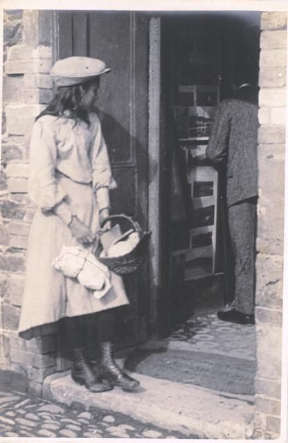 an old black and white photo of two people standing in front of a store door