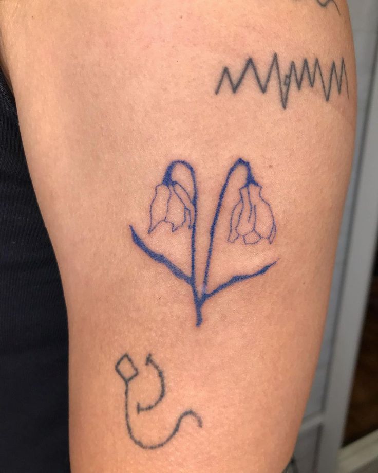 a tattoo on the arm of a woman with flowers and heartbeats in blue ink