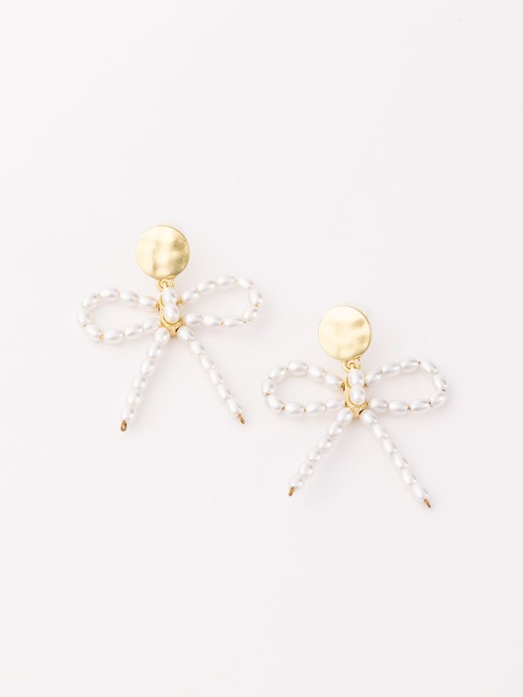 Add a touch of elegance and charm to your ensemble with the Blair Earrings. These stunning earrings feature pearls meticulously shaped into a delicate bow, creating a perfect blend of sophistication and whimsy. Ideal for both special occasions and everyday wear, the Blair Earrings bring a graceful and timeless appeal to any outfit. Details Length: 1" Pearl accent detail Brass plated metal Hypoallergenic Surgical steel posts Nickel and lead free Care Instructions Avoiding contact with lotion, per Elegant Butterfly Knot Drop Earrings, Feminine Pearl Drop Earrings, Chic Pearl Drop Earrings As Gift, Elegant Butterfly Knot Earrings For Wedding, Elegant Wedding Earrings With Butterfly Knot, Chic Pearl Drop Earrings For Gift, Elegant Drop Earrings With Butterfly Knot Detail, Formal Pearl Drop Earrings With Bow, Feminine White Pearl Earrings For Evening