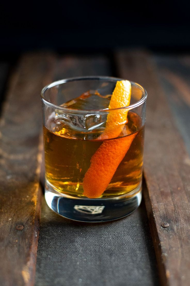 an orange peel sitting on top of a glass filled with liquid next to a wooden table