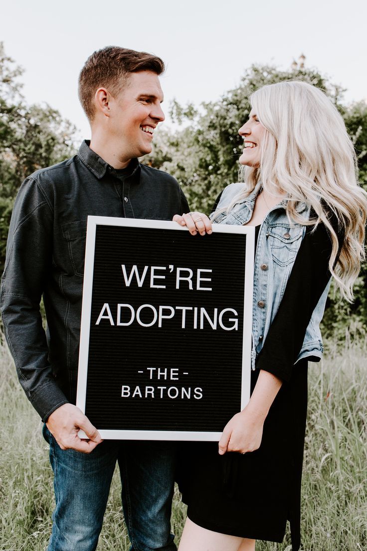 a man and woman holding a sign that says we're adoptting the bartons