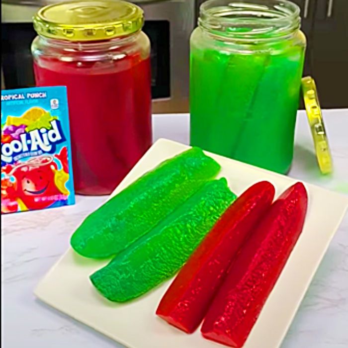 pickles and jello on a white plate next to a box of gummy bears