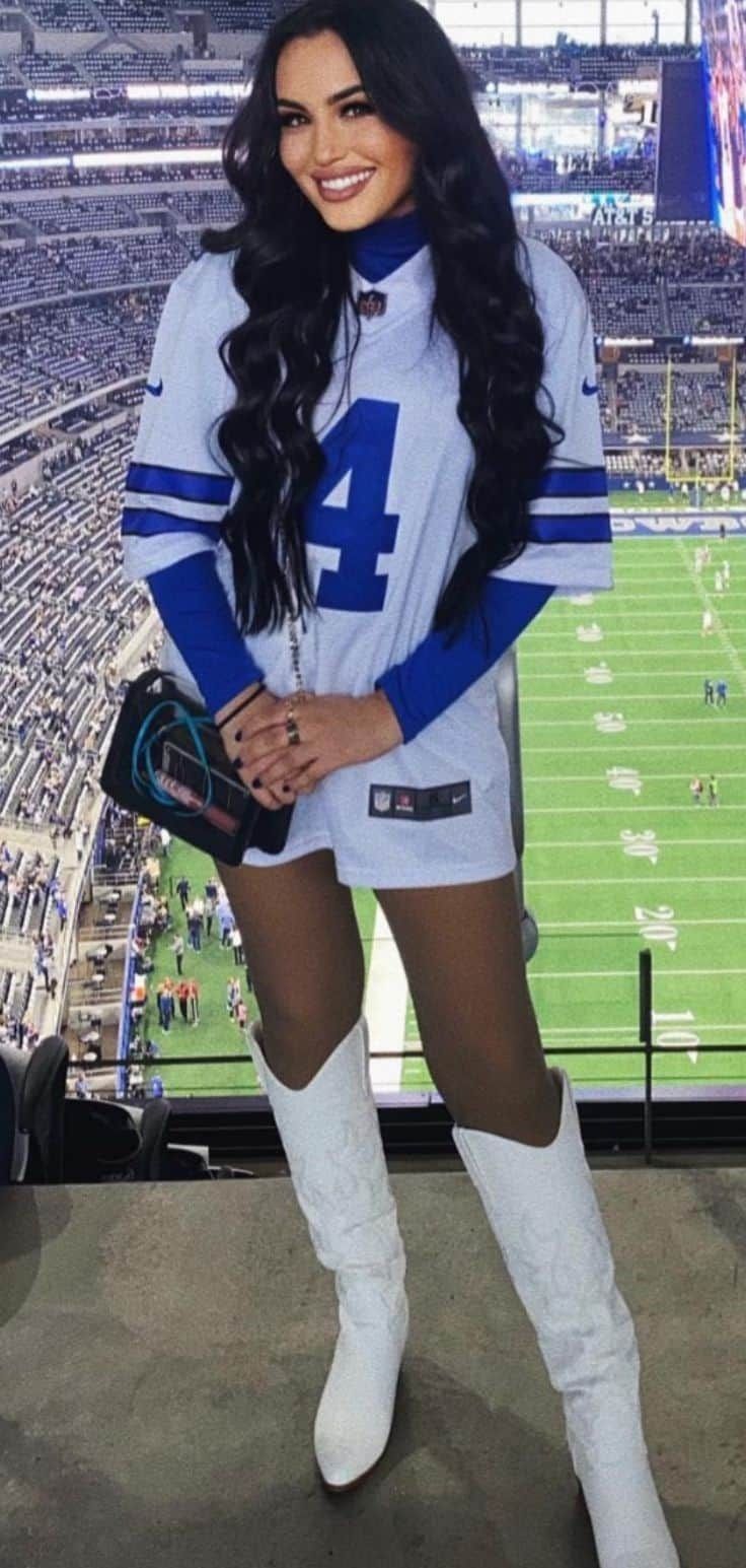 a woman posing for a photo in front of a football stadium with the number 4 on her jersey