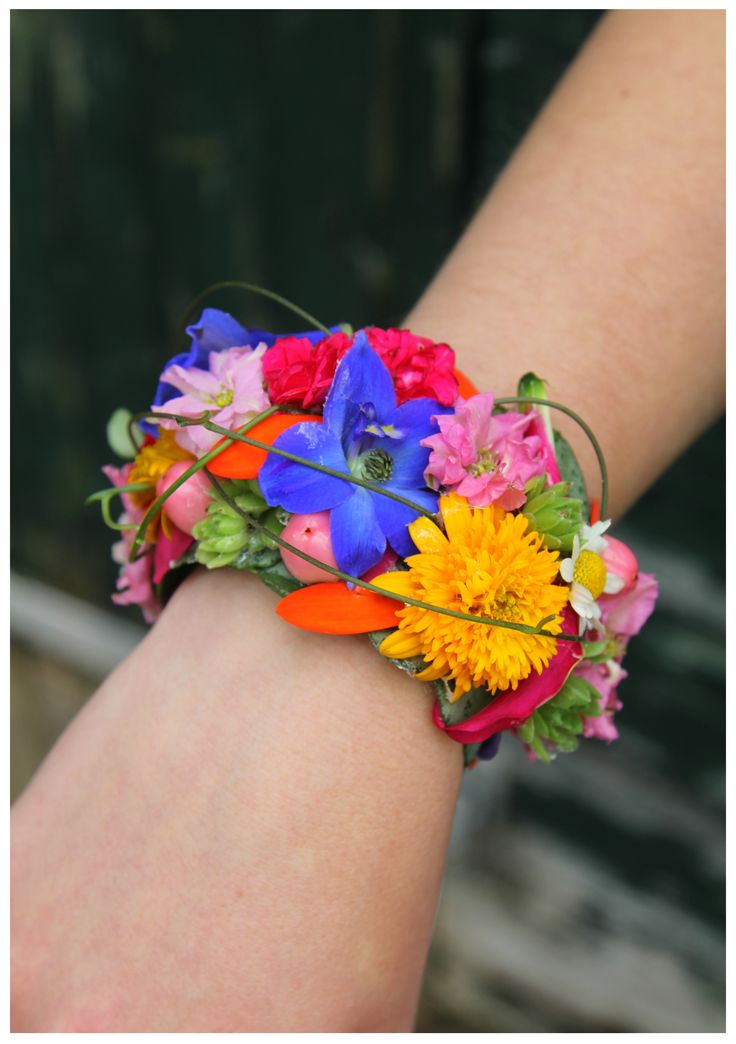 a woman's arm with a colorful flower bracelet on her left wrist and flowers in the middle