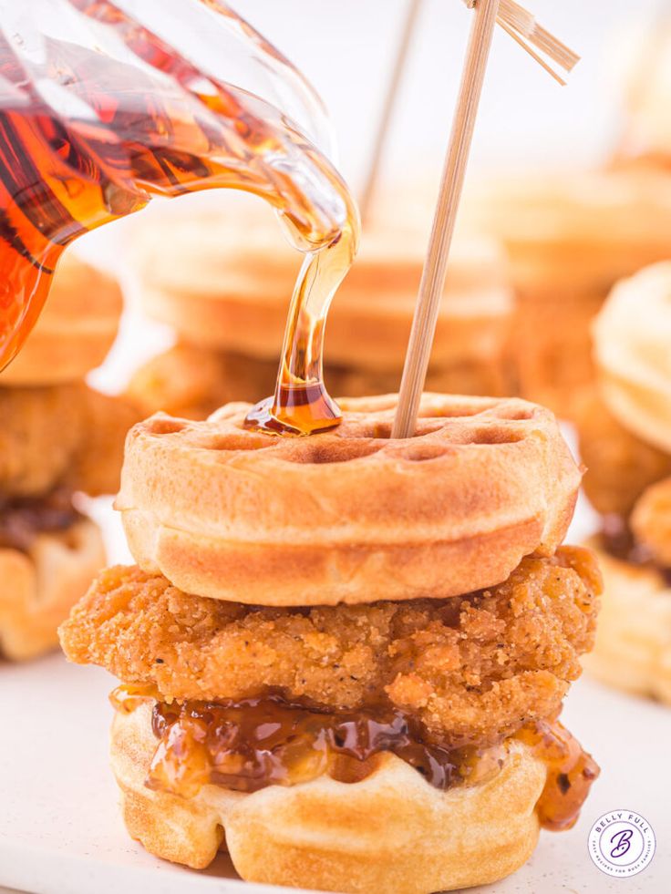 a stack of fried chicken and waffles being drizzled with syrup