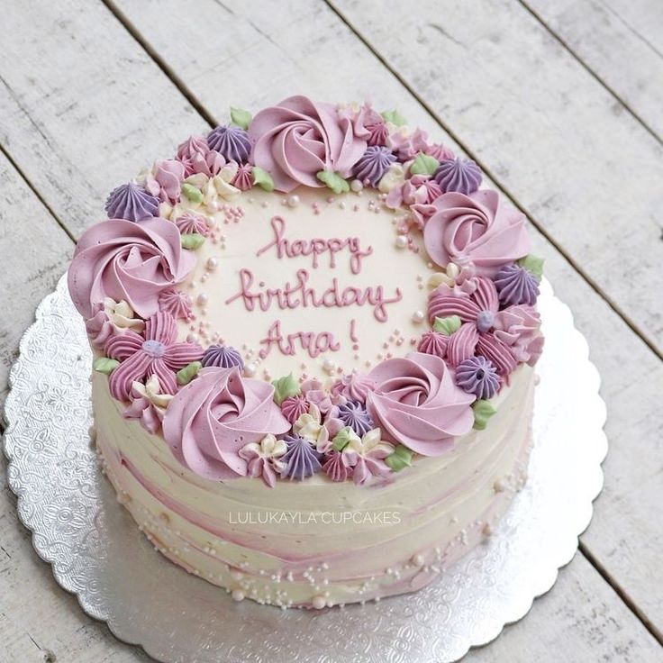 a birthday cake with pink frosting and purple flowers