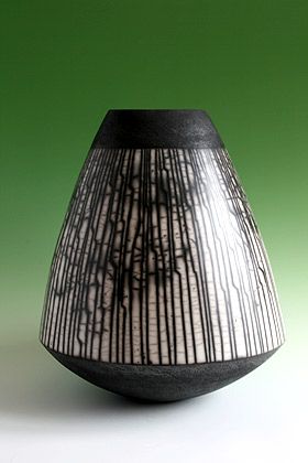 a black and white vase sitting on top of a green table next to a wall