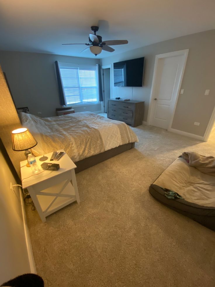 a bedroom with a bed, dresser and ceiling fan in the middle of the room