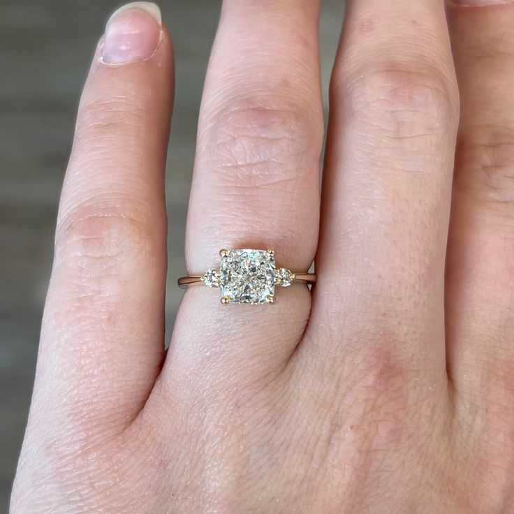 a woman's hand with a diamond ring on top of her finger and an engagement band