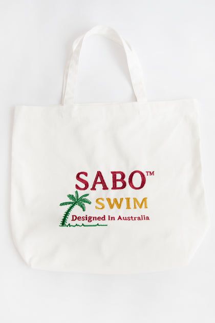 Seaside Tote Bag Summer Shopping Bags With Embroidered Logo, White Travel Bag With Embroidered Logo, Summer Rectangular Bag With Embroidered Logo, Cream Cotton Bag For Vacation, White Bags With Embroidered Logo For Shopping, Casual White Embroidered Canvas Bag, Eco-friendly White Embroidered Canvas Bag, White Cotton Canvas Bag For Beach Season, Summer Embroidered Canvas Bag For Everyday Use