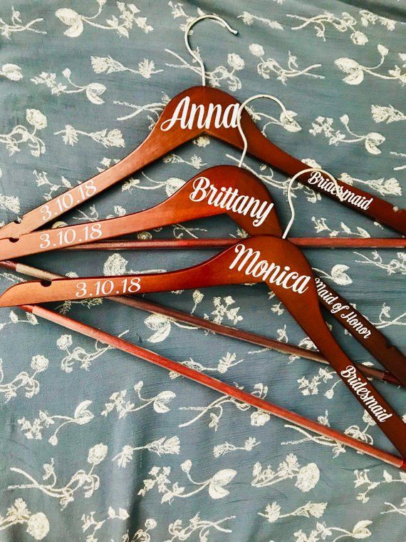 four wooden hangers with names on them sitting on a floral print bed spreader