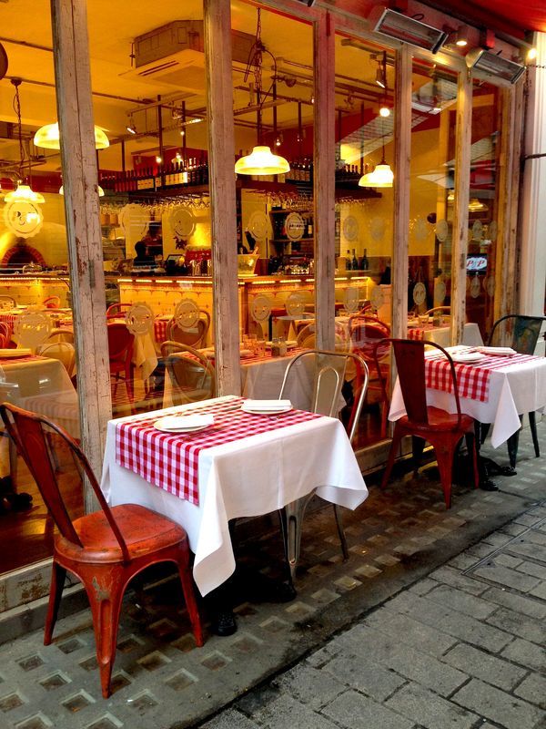 a restaurant with tables and chairs in front of the storefront, all set up for dinner