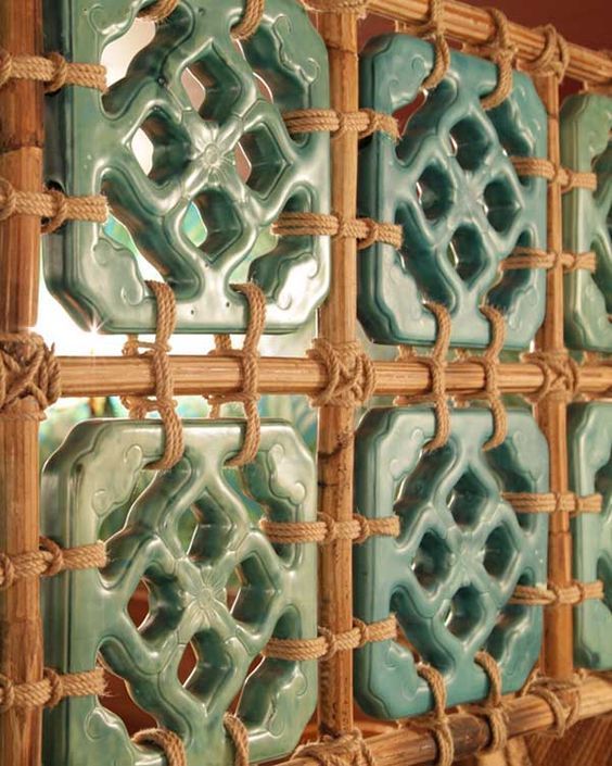 decorative ceramic tiles are displayed on a shelf in a room that is decorated with wood and rope