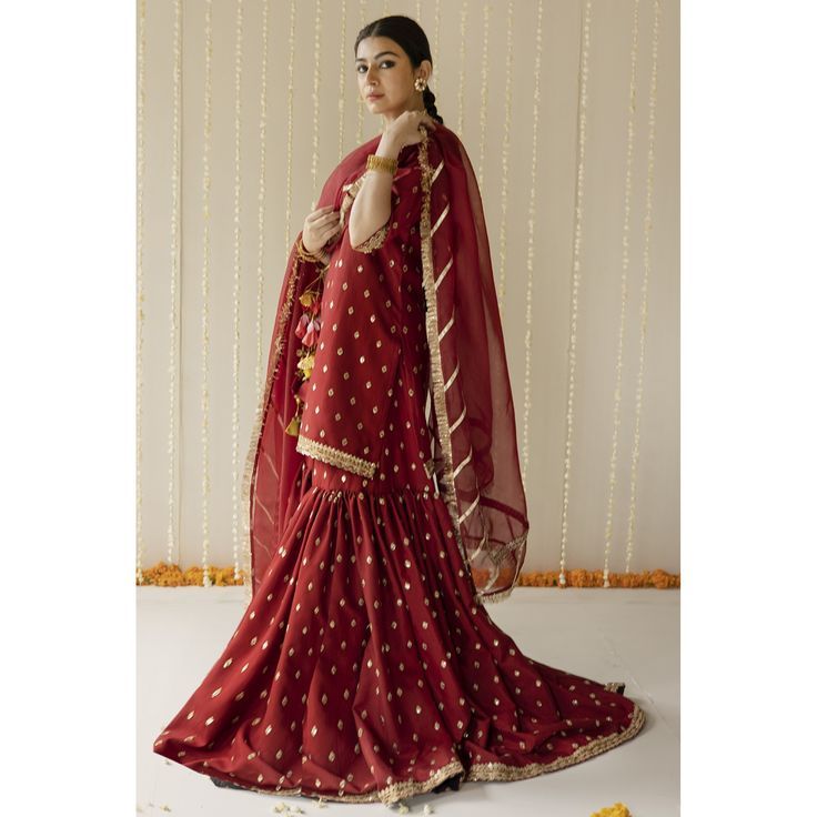 a woman wearing a red and gold lehenga with white polka dots on it