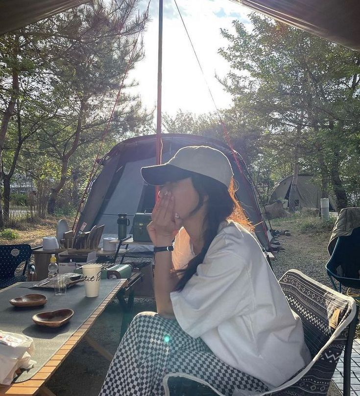 a woman sitting at a table with an umbrella over her head and food in front of her