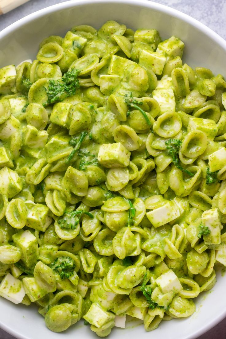 a white bowl filled with green pasta and broccoli