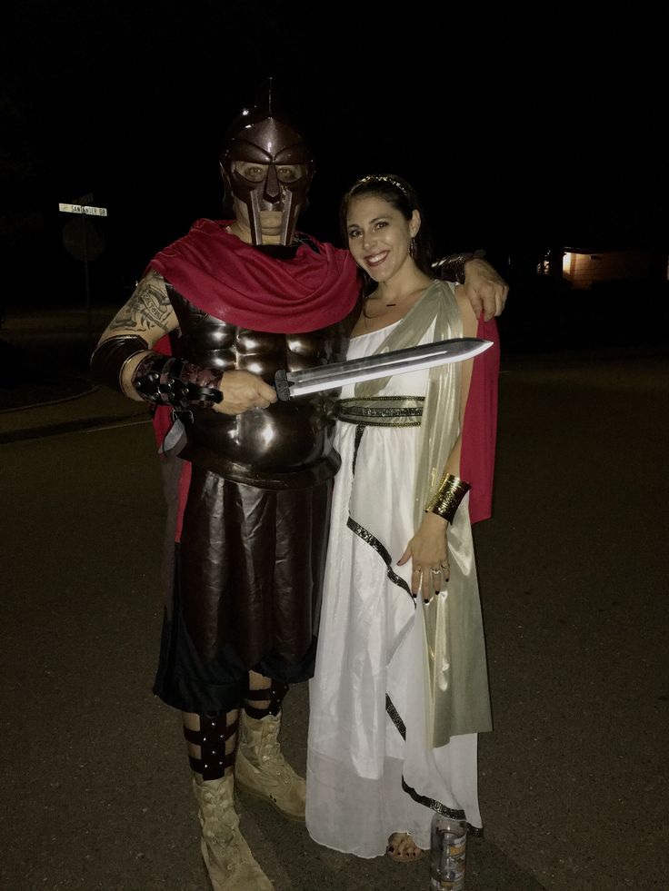 a man and woman dressed up as roman soldiers pose for a photo together at night