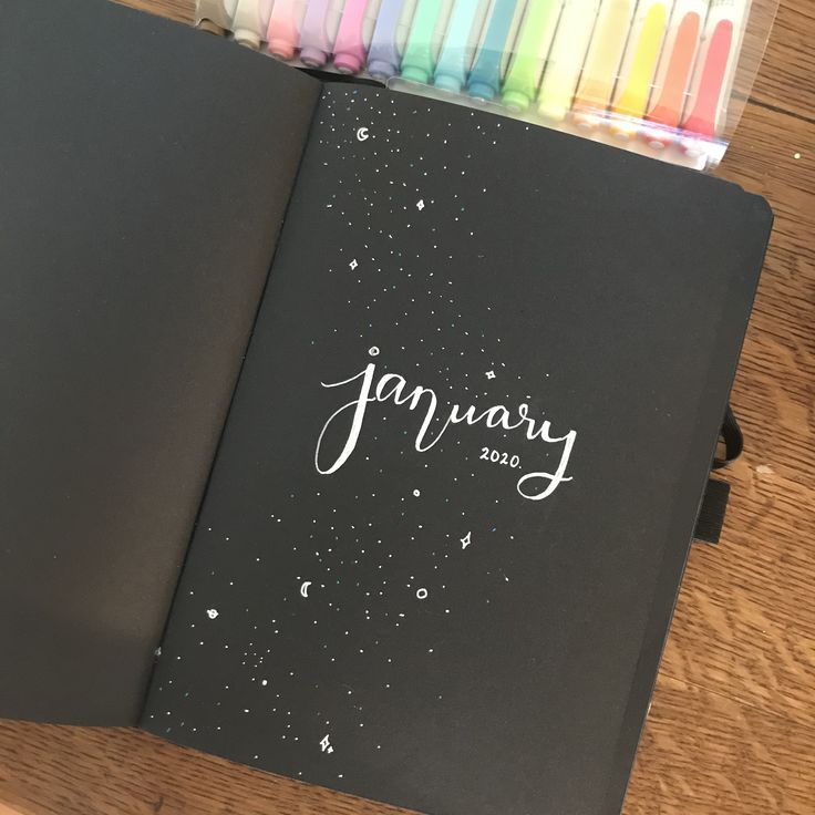 an open notebook with the word january written in white on it next to colored crayons