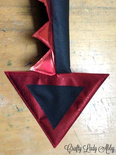 a red and black triangle on top of a wooden table next to a piece of cloth