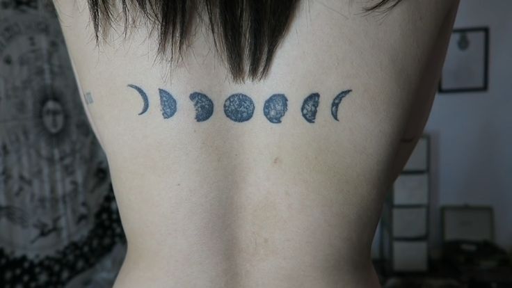 the back of a woman's neck with phases tattooed on her left shoulder and chest