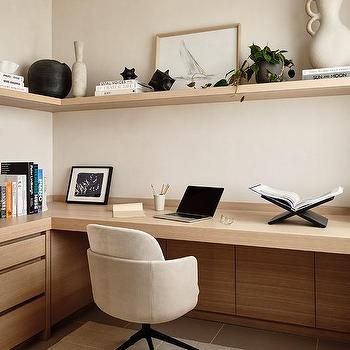 a desk with a laptop and books on it in front of a wall mounted vase