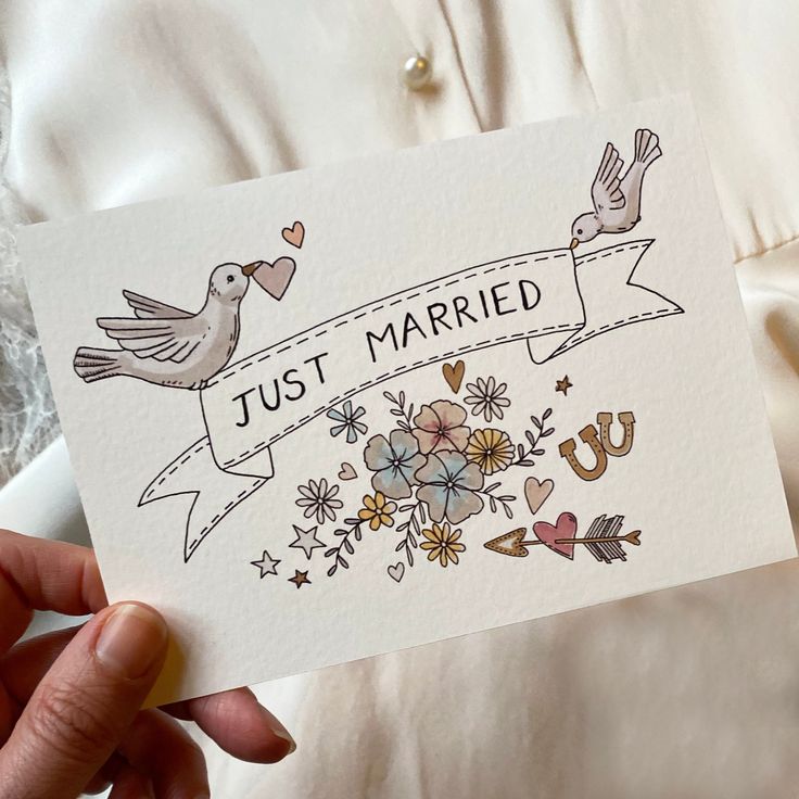 a person holding up a card that says just married with birds and flowers on it