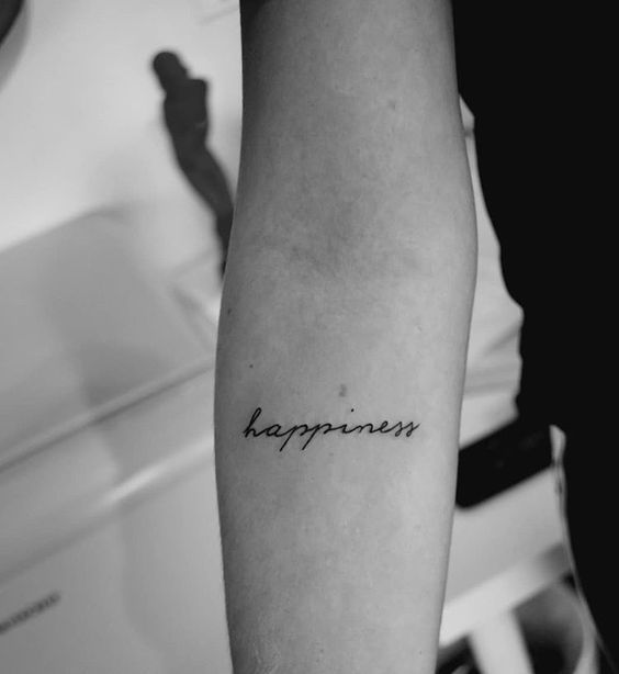 a black and white photo of a person's arm with the word happiness tattooed on it