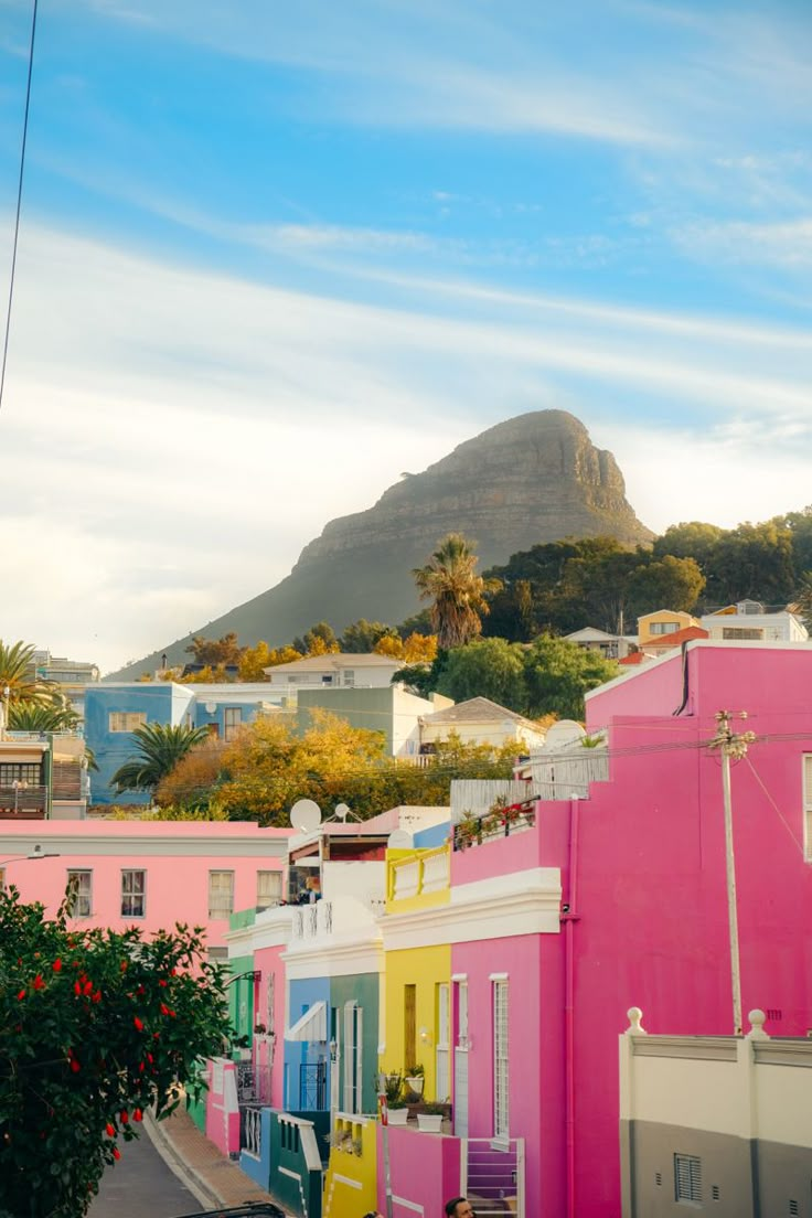 colorful houses line the street with a mountain in the background