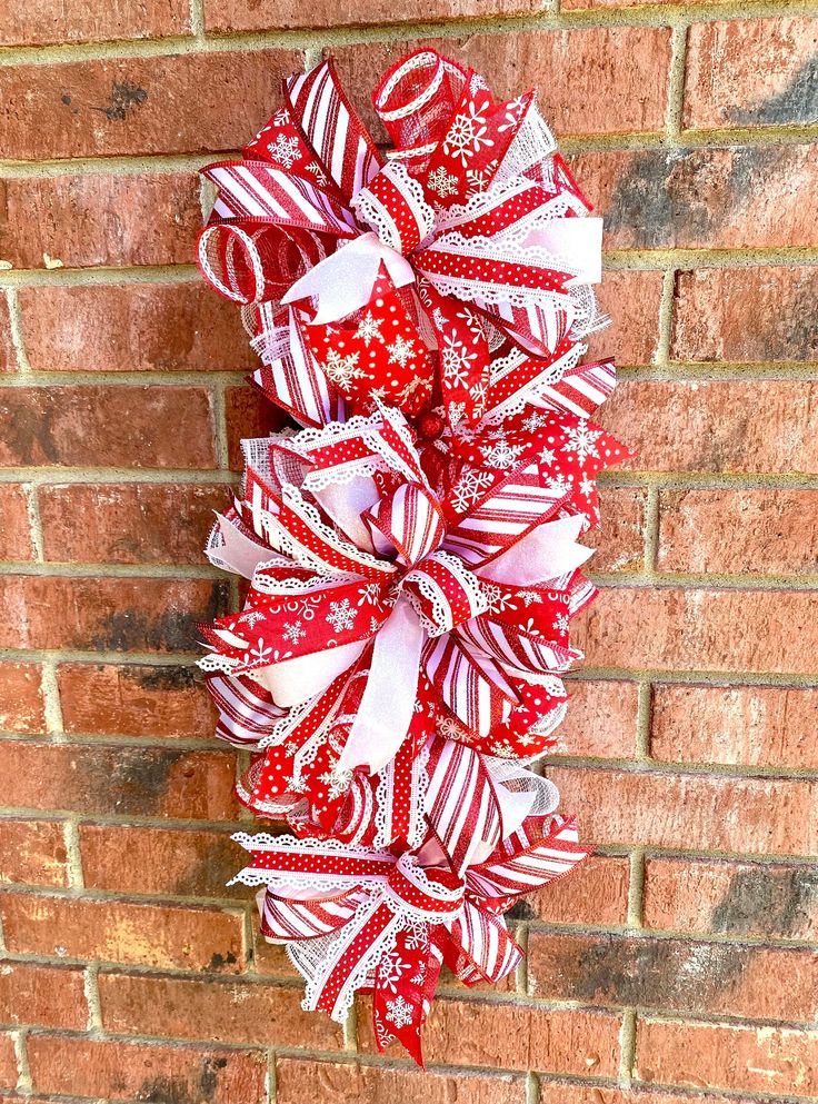 a red and white christmas bow hanging on a brick wall