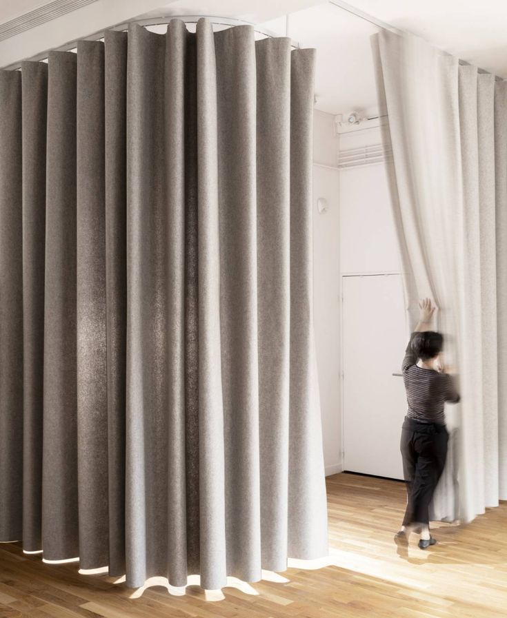 a person standing in front of a curtain with the curtains pulled back to reveal light