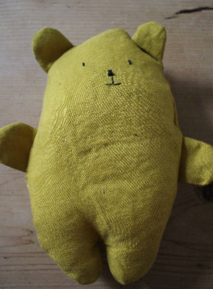 a yellow teddy bear sitting on top of a wooden floor