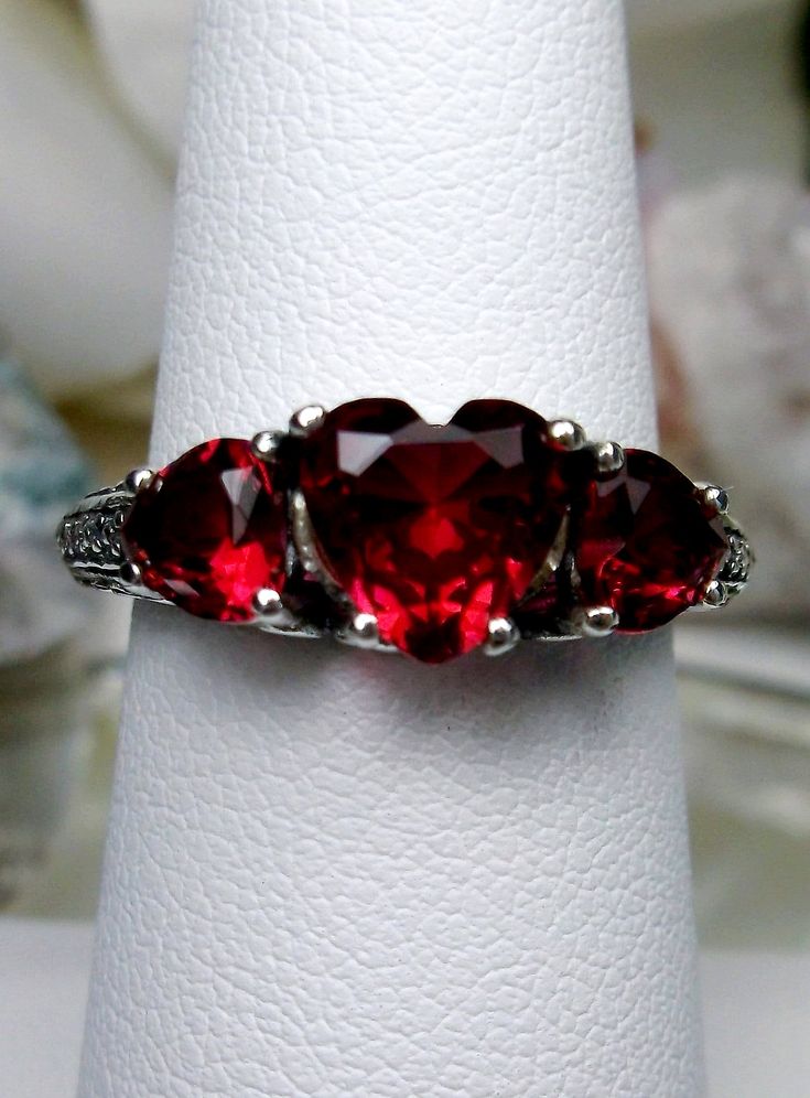 3Gem Simulated Red Ruby Ring Hearts Design#143 Custom Made This is a lovely Edwardian inspired ring in solid sterling silver. The gorgeous filigree ring is set with 3 heart cut simulated/Man-made ruby red gemstones. The 2 smaller gems are 5mm in diameter, and the center one is 7mm in diameter. Notice the amazing etched band... The ring sits 1/4th" (7mm) off the finger. The quality of the silver and gemstones are simply breathtaking... a ring that will last for countless years to come... The insi Red Ruby Ring, Star Ruby Ring, Ruby Heart, Zierlicher Ring, Red Gemstones, Heart Gemstone, Sterling Silver Filigree, Lovely Ring, Filigree Ring